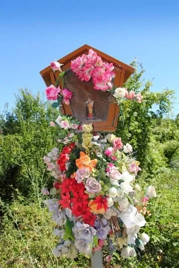 Pequeño altar en medio de uin camino, dedicado a la Virgen María. Adornado con flores.